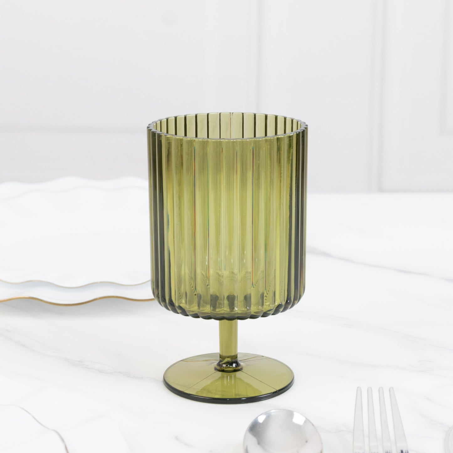 Dusty sage green ribbed plastic goblet on a marble table