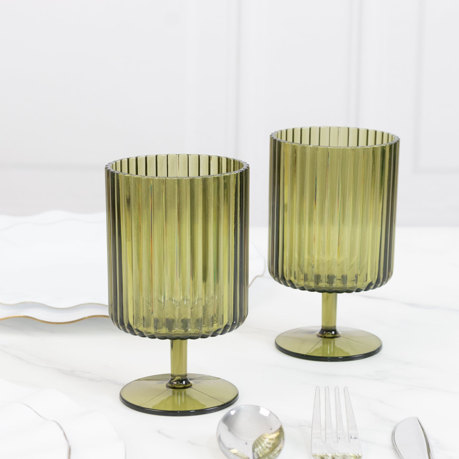 Dusty sage green vintage ribbed pattern plastic goblets on a table.