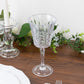 Clear shatterproof cocktail glass with embossed leaf pattern on a wooden table.