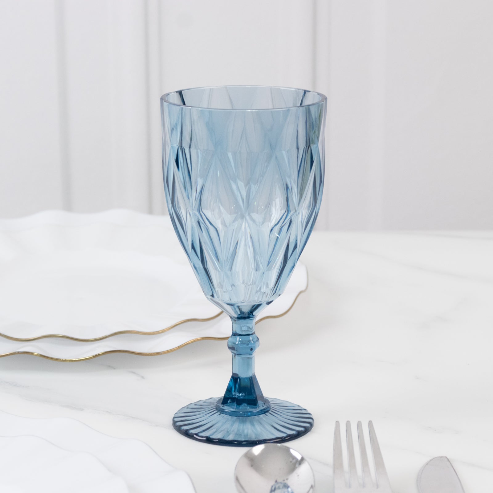 Dusty blue vintage diamond cut plastic goblet on a marble surface.
