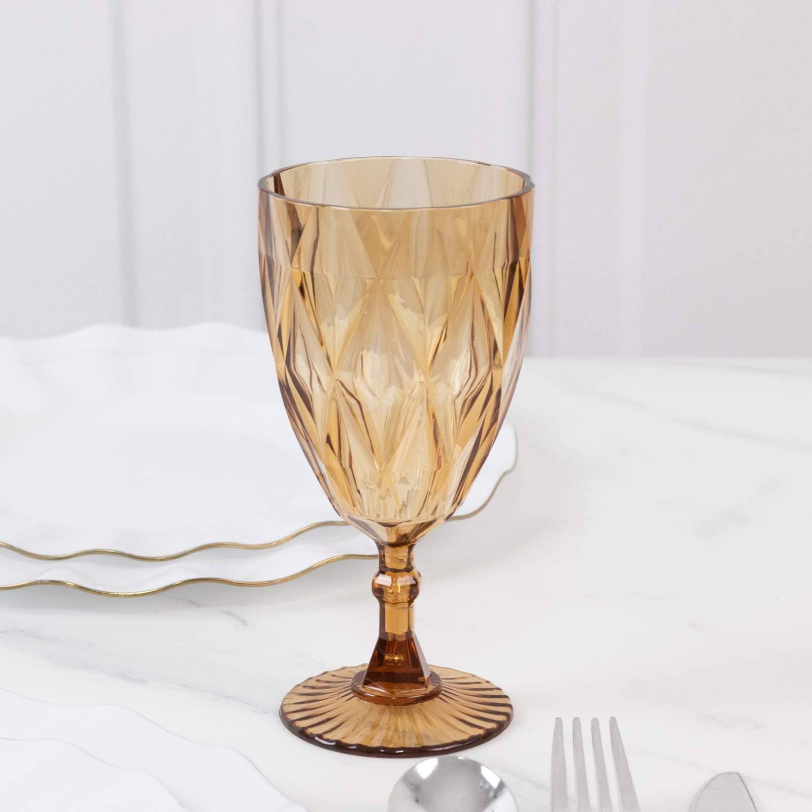Amber gold vintage diamond cut plastic goblet on a marble surface.