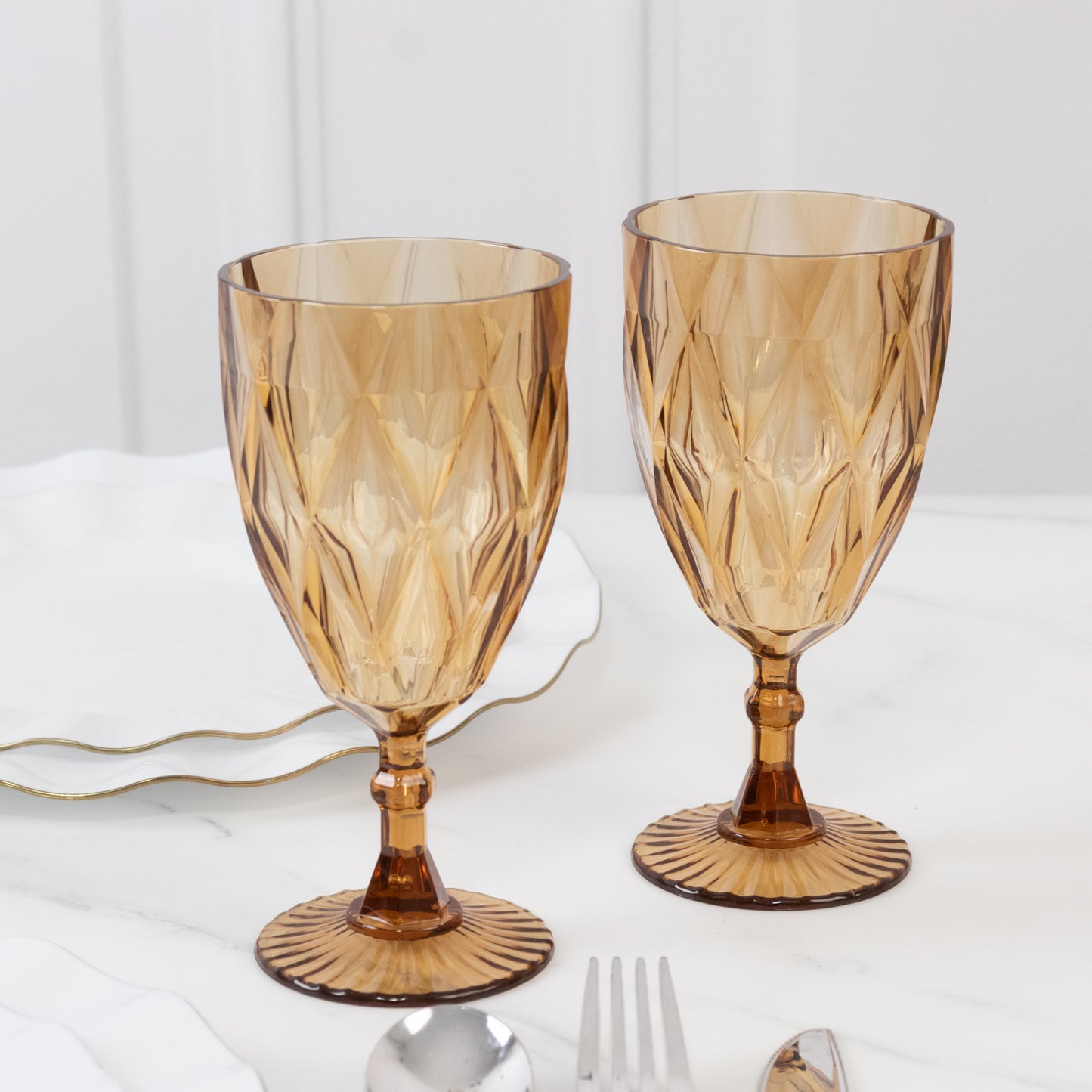 Amber gold vintage diamond cut plastic goblets on a table setting.