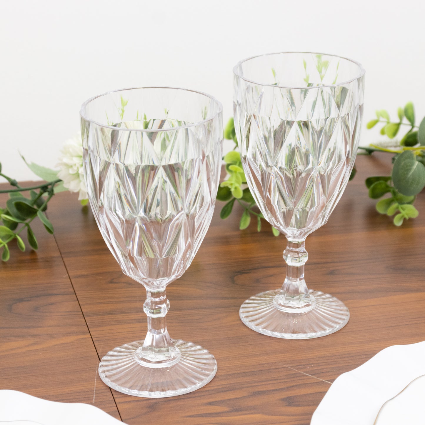 Clear vintage diamond cut plastic goblets on a wooden surface.