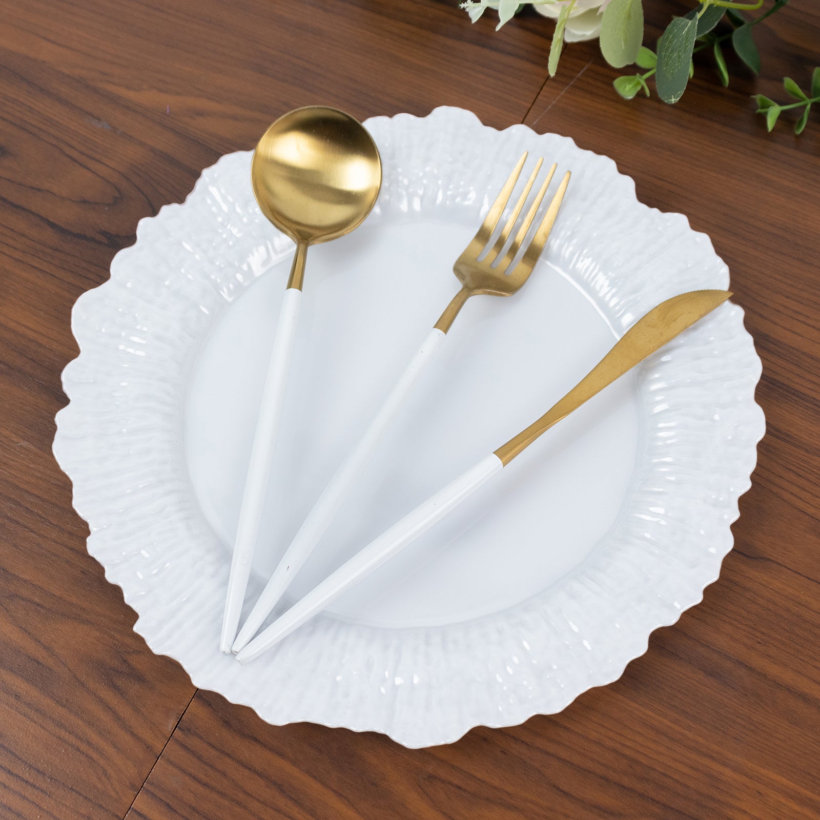 Pearl white plastic dinner plate with elegant reef design and gold utensils.