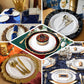 White plastic dinner plate with royal blue rim and gold vine design.