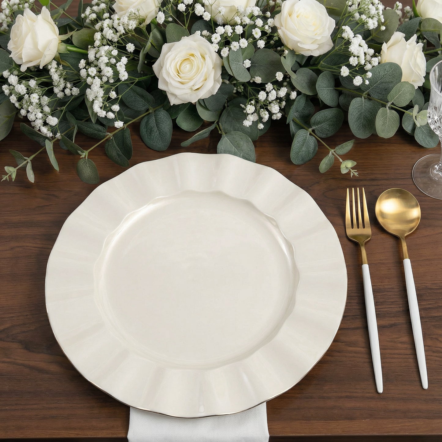 Pearl white ruffled rim dinner plate with gold edging on a wooden table.