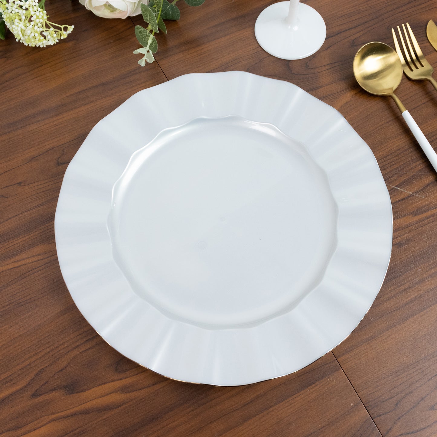 Pearl white round dinner plate with ruffled rim and gold edging on a wooden table.