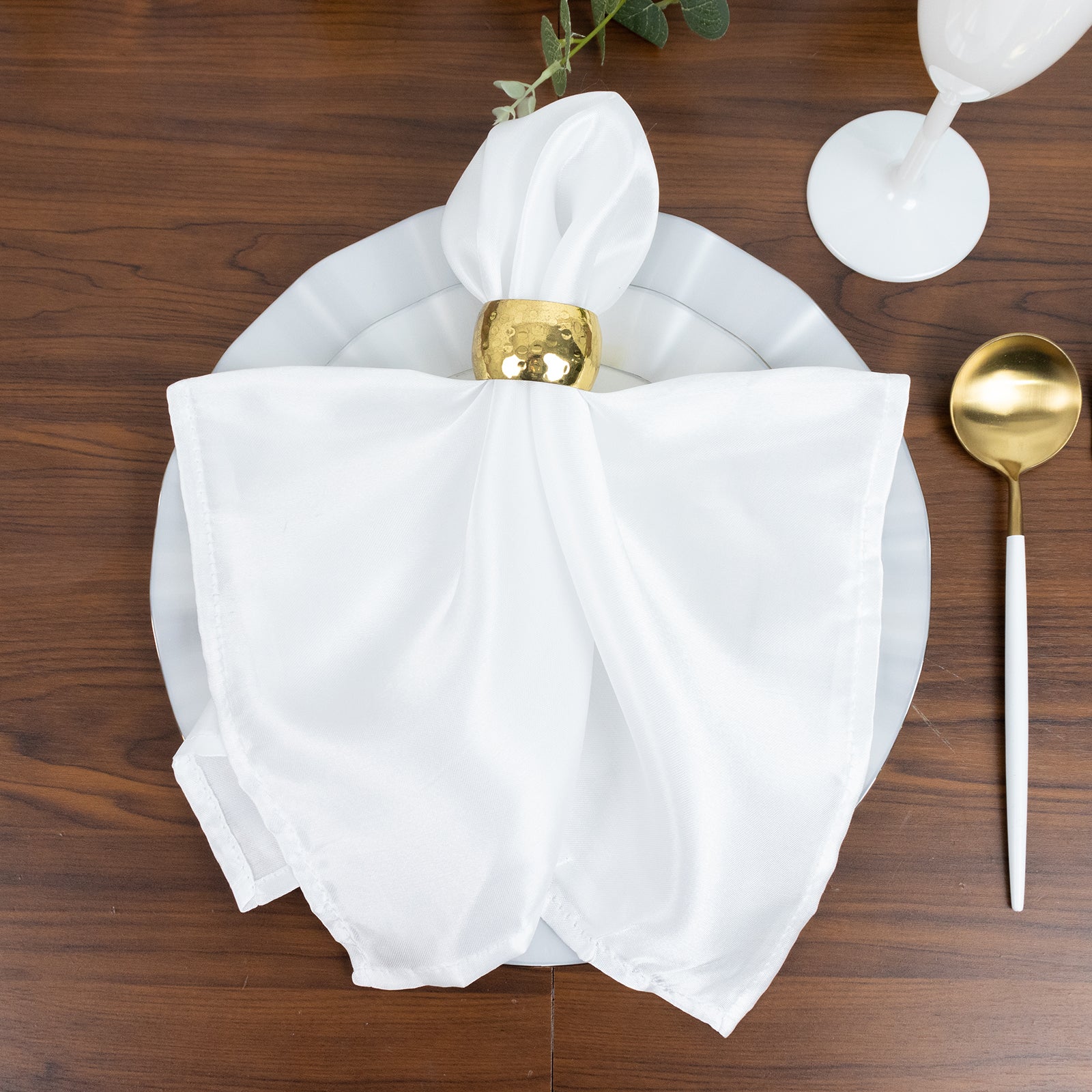 Pearl white round dessert plate with gold edging on a wooden table setting.