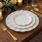Pearl white ruffled rim dessert plates with gold edging on a wooden table.