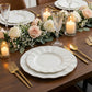 Pearl white ruffled rim dinner plates with gold edging on a dining table.