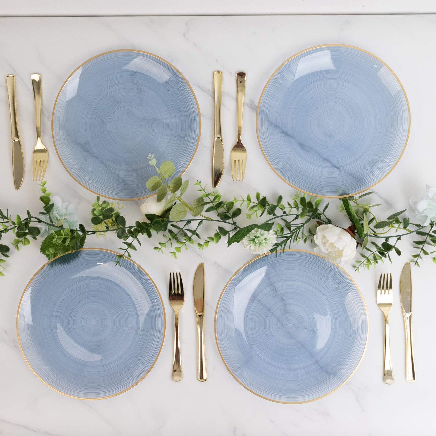 Round transparent dusty blue swirl plates with gold rim on a marble surface.