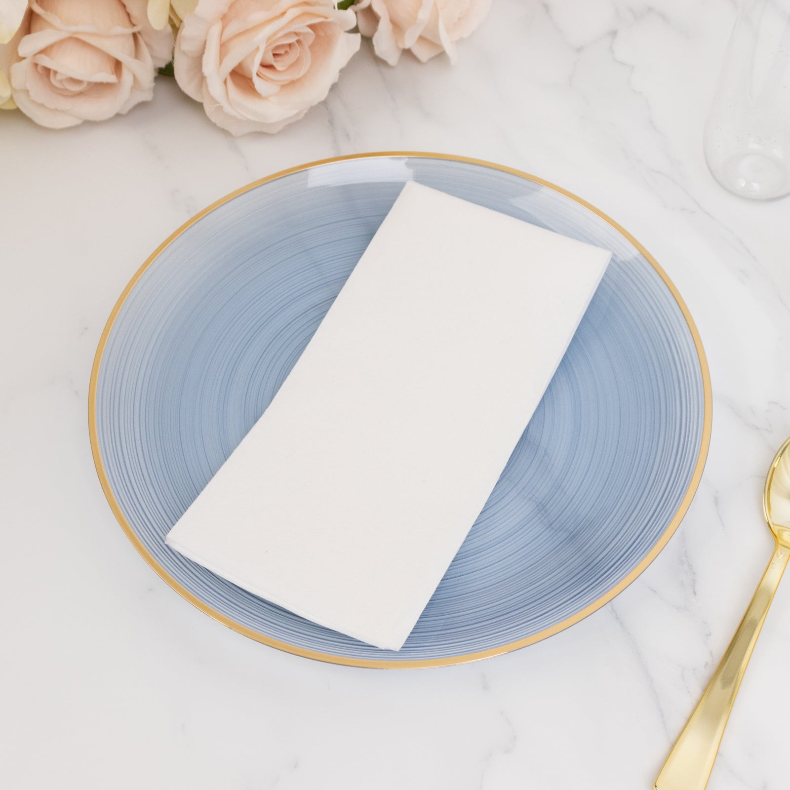 Transparent dusty blue swirl plate with gold rim on a marble table.