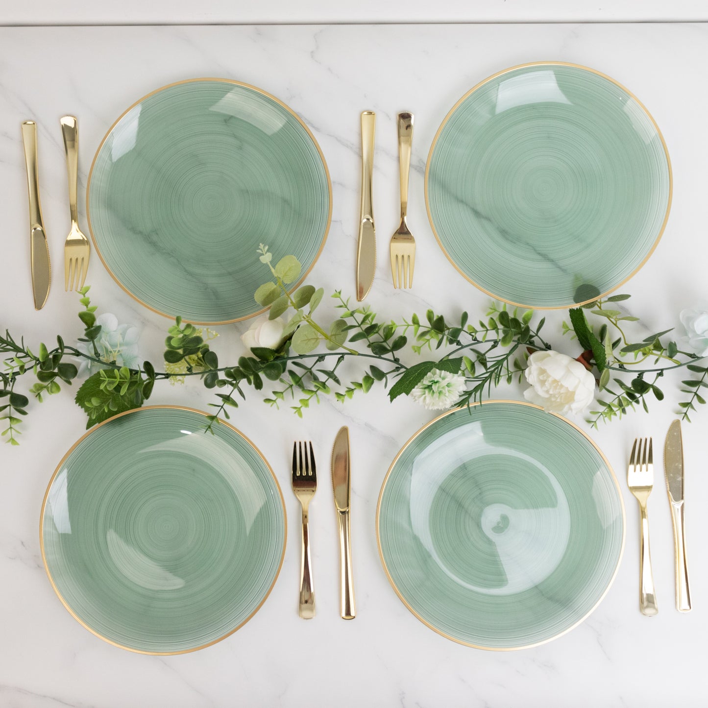 Dusty sage green swirl plates with gold rim on a marble table setting.