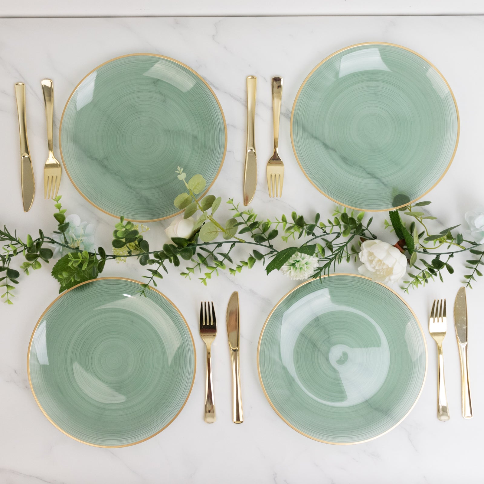 Dusty sage green swirl plates with gold rim on a marble table setting.