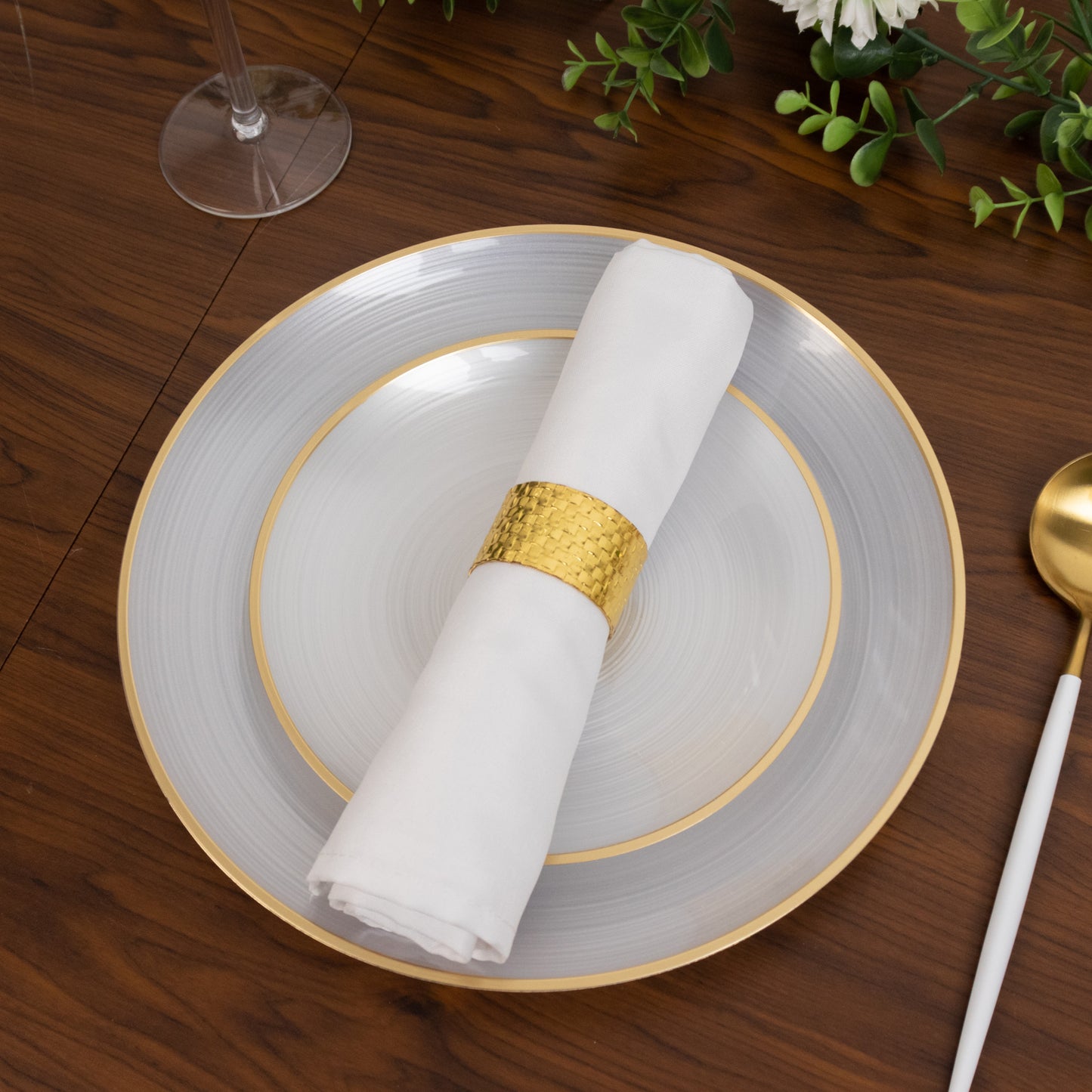 Round transparent pearl white swirl plate with a gold rim, elegant party setting.