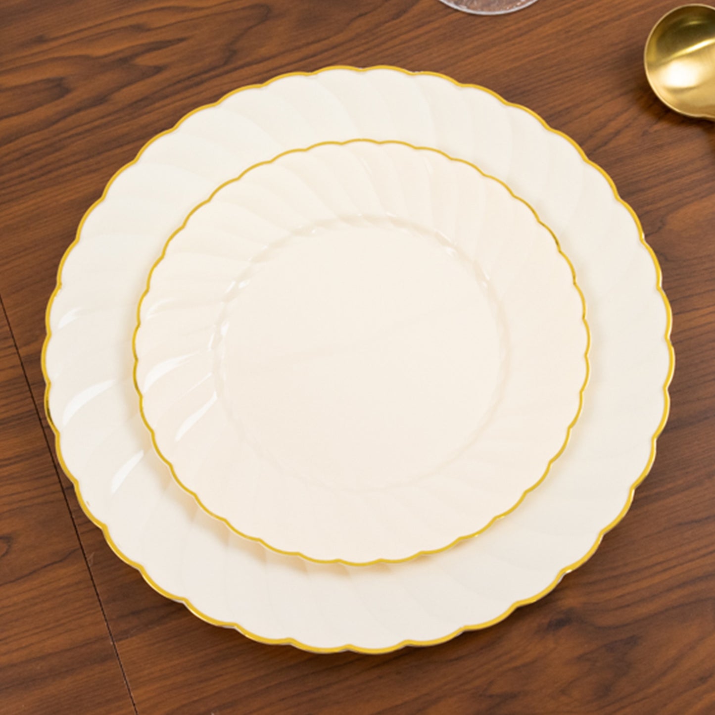 Ivory and gold flair rim disposable dessert plates on a wooden table.