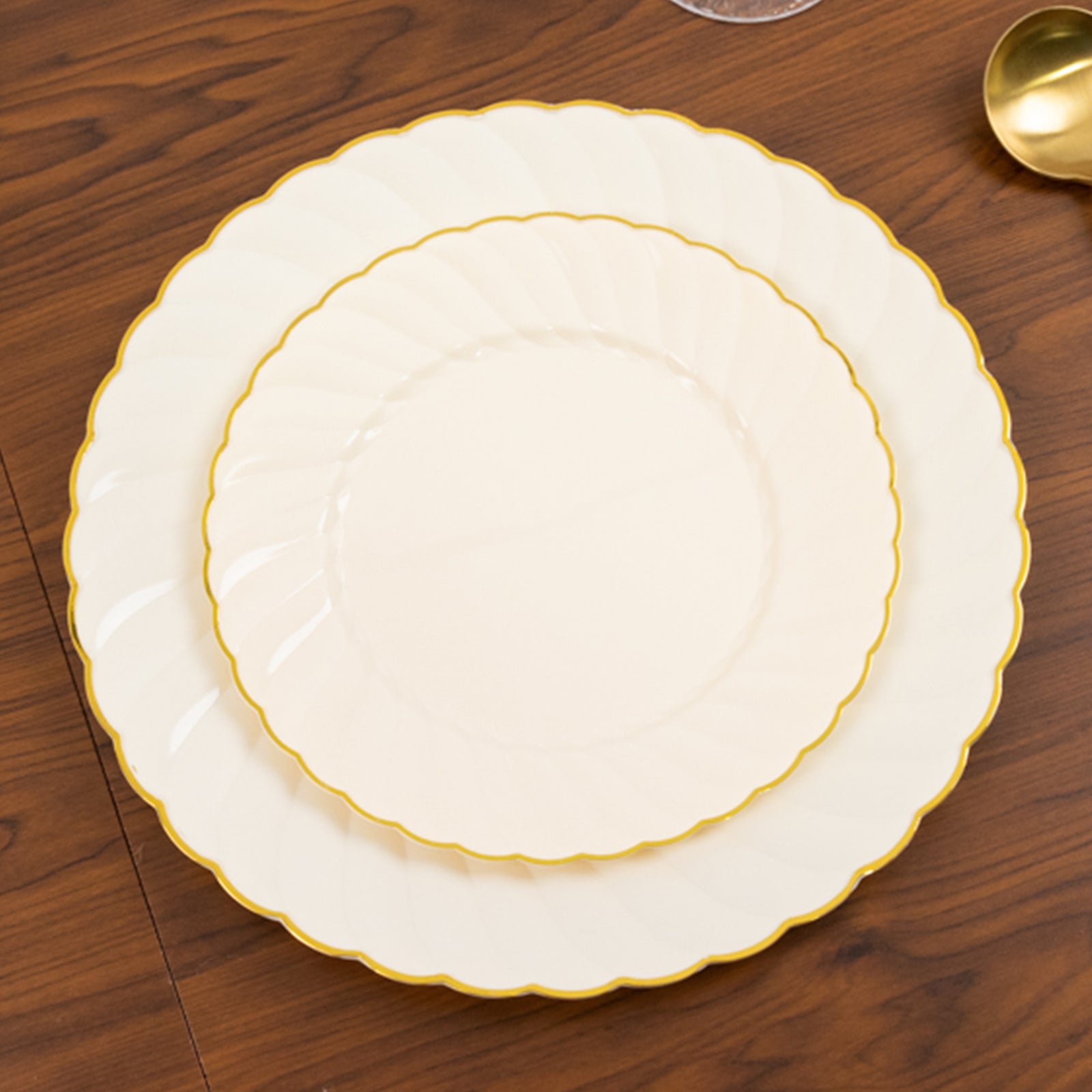 Ivory and gold flair rim disposable dessert plates on a wooden table.