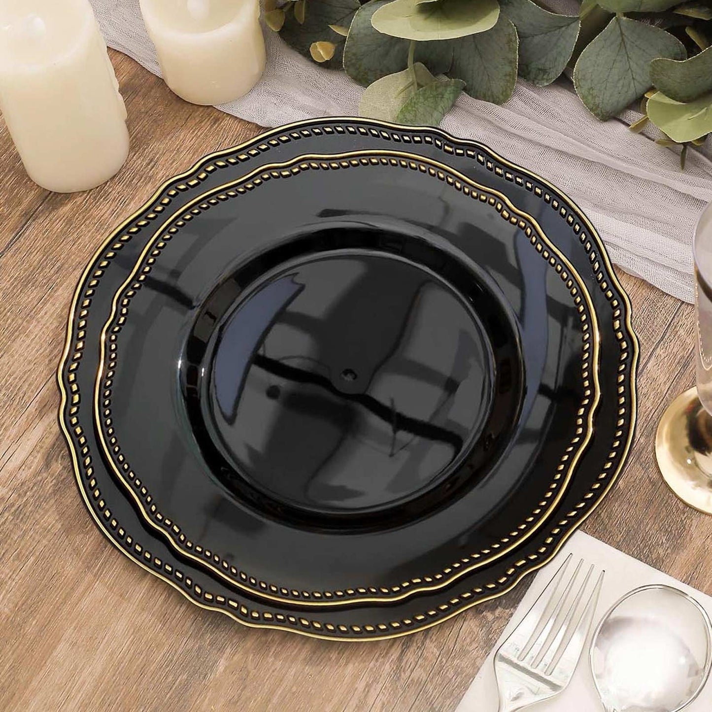 9" Black and Gold Scalloped Rim Plastic Dinner Plate on a wooden table.