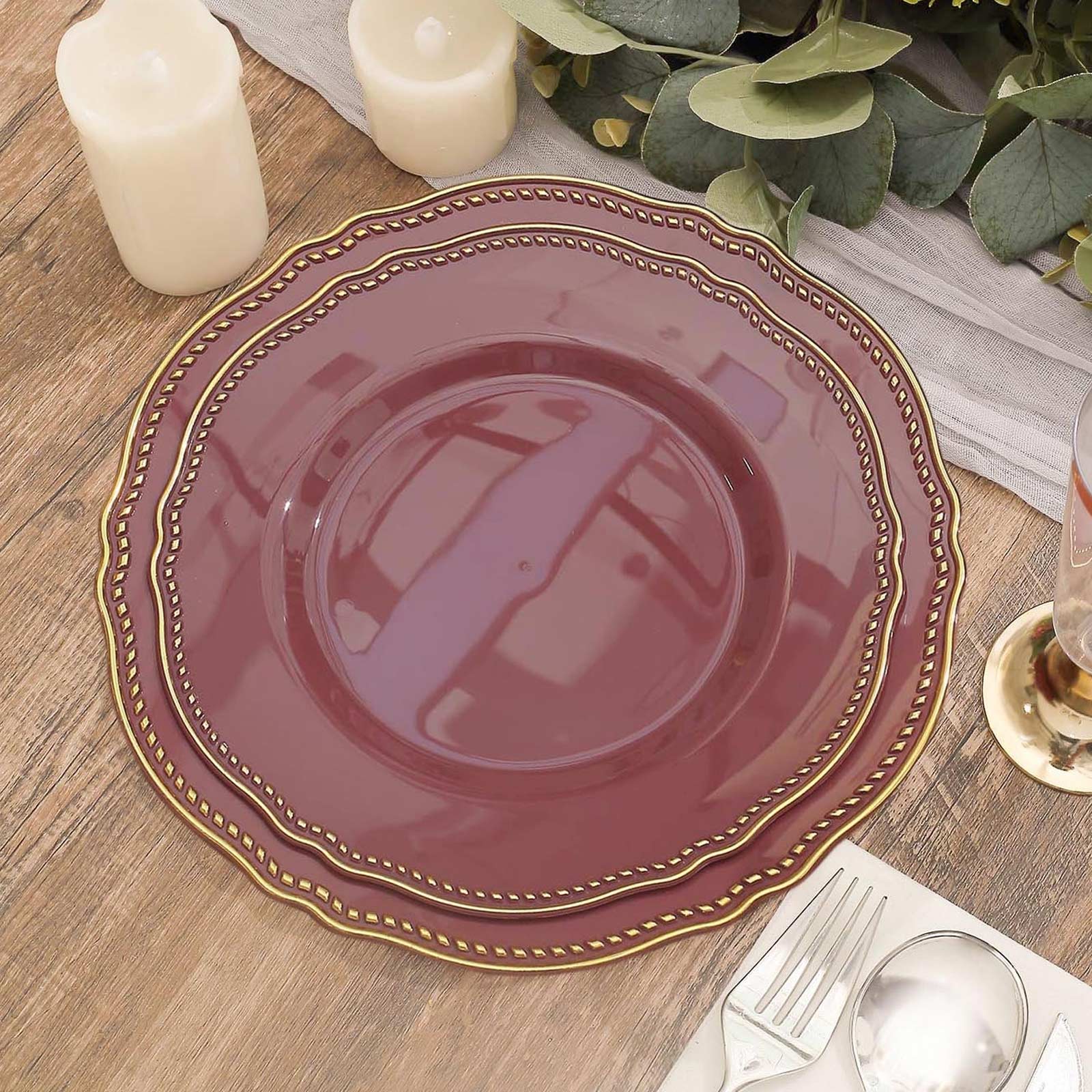 Elegant burgundy charger plate with gold trim on a wooden table setting.