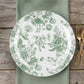 Sage green and white floral disposable dinner plate on a wooden table.