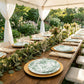 Sage green and white floral disposable salad plates set on a rustic table.