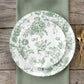 Sage green and white floral disposable salad plates on a wooden table.