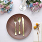 Rustic brown melamine dinner plate with gold utensils on a table setting.