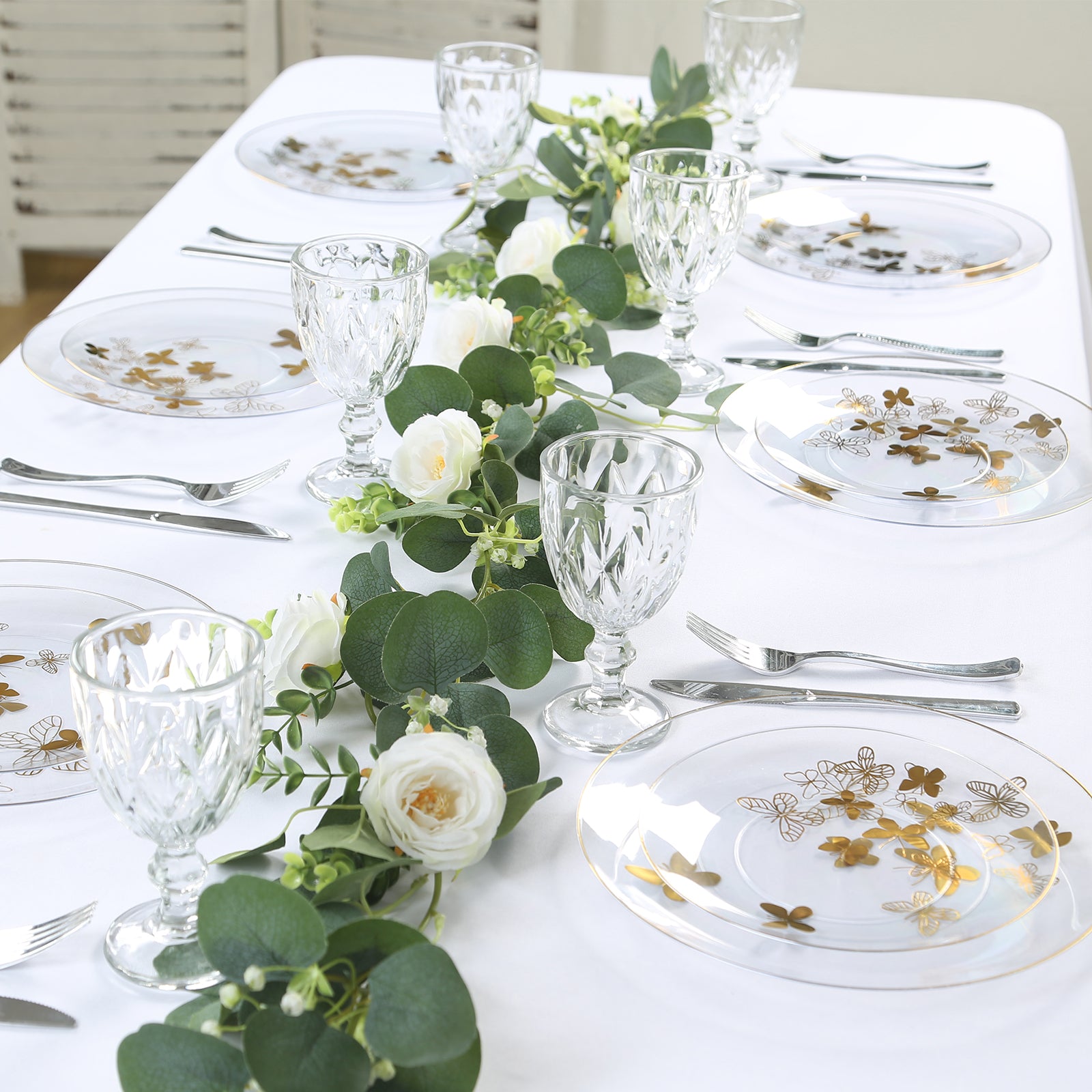 Clear gold butterfly plastic party plates with gold rim on a table setting.