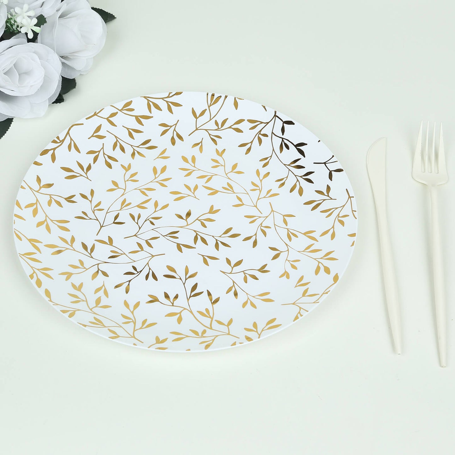 White round plastic party plate with gold leaf design.