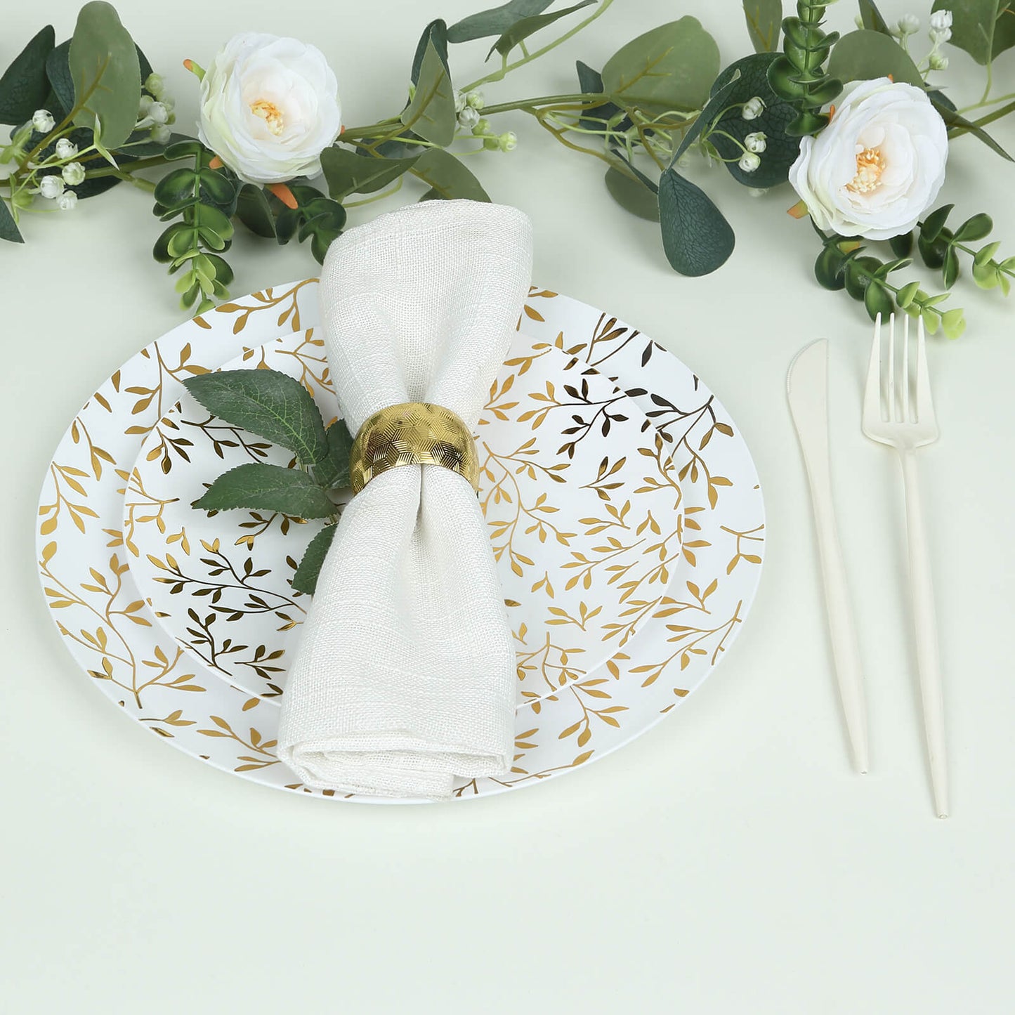 White round plastic party plate with gold leaf design, heavy duty disposable.