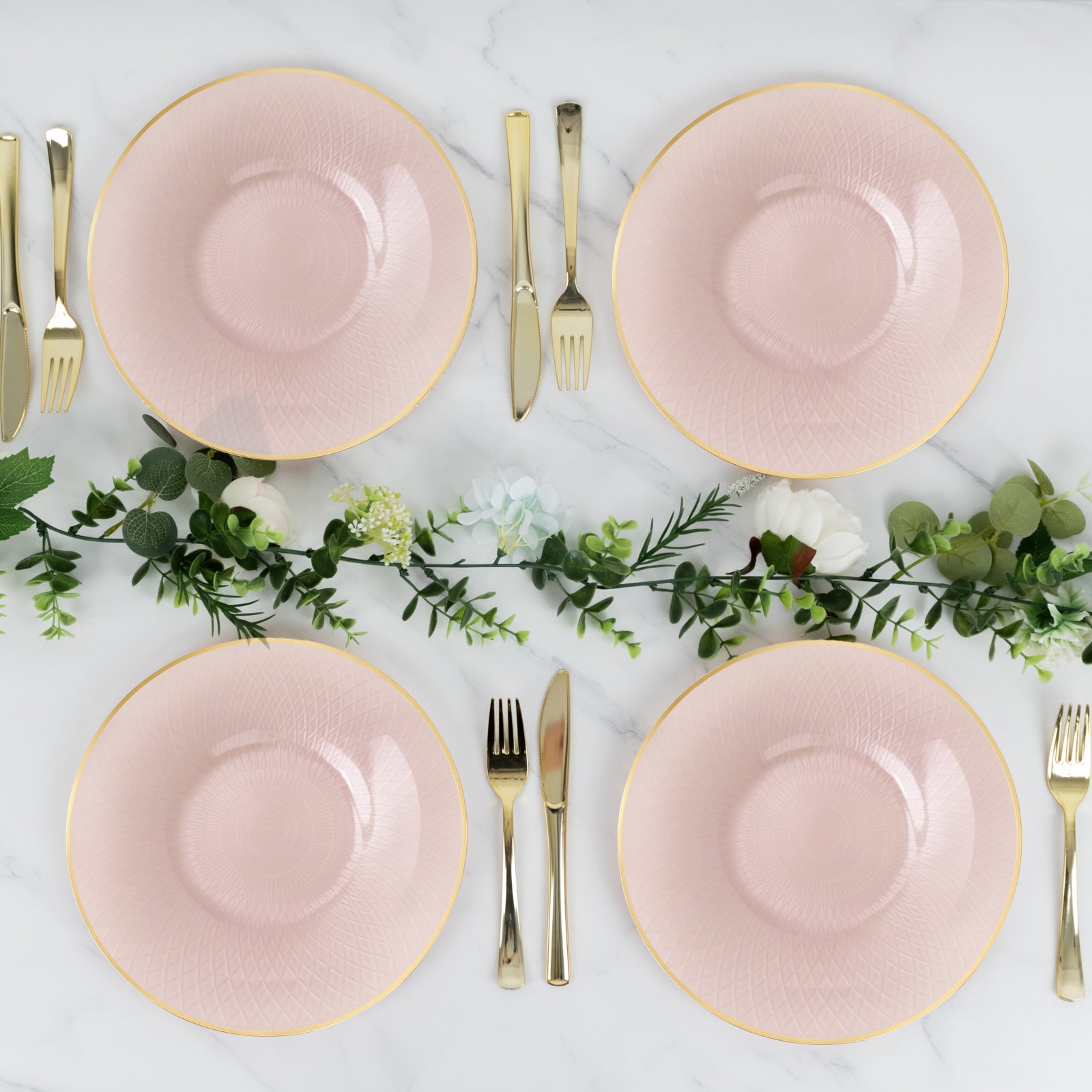 Blush pink dinner plates with gold rim and diamond-cut pattern, set for a party.