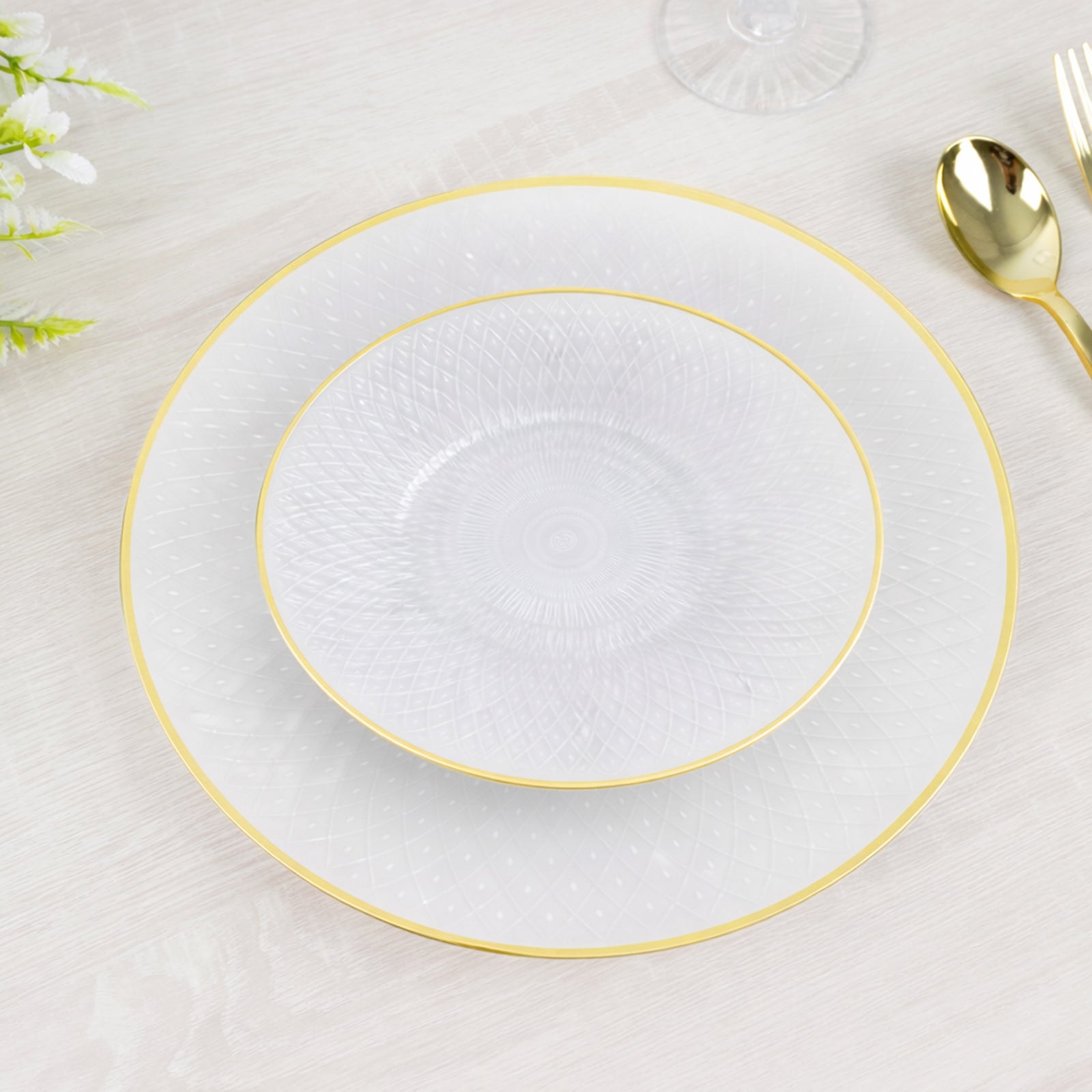 Round pearl white disposable plates with gold rim and diamond-cut pattern.