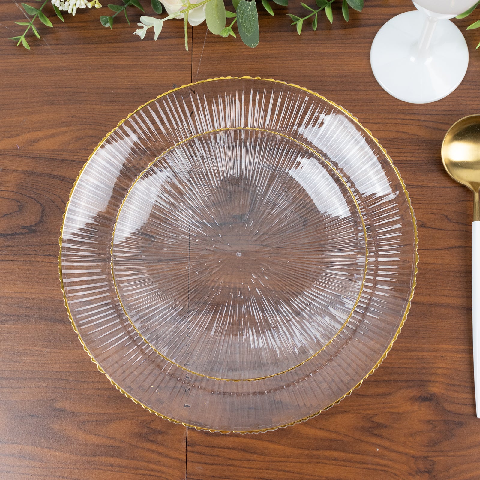 Clear plastic dinner plate with gold rim and ribbed sunburst pattern.