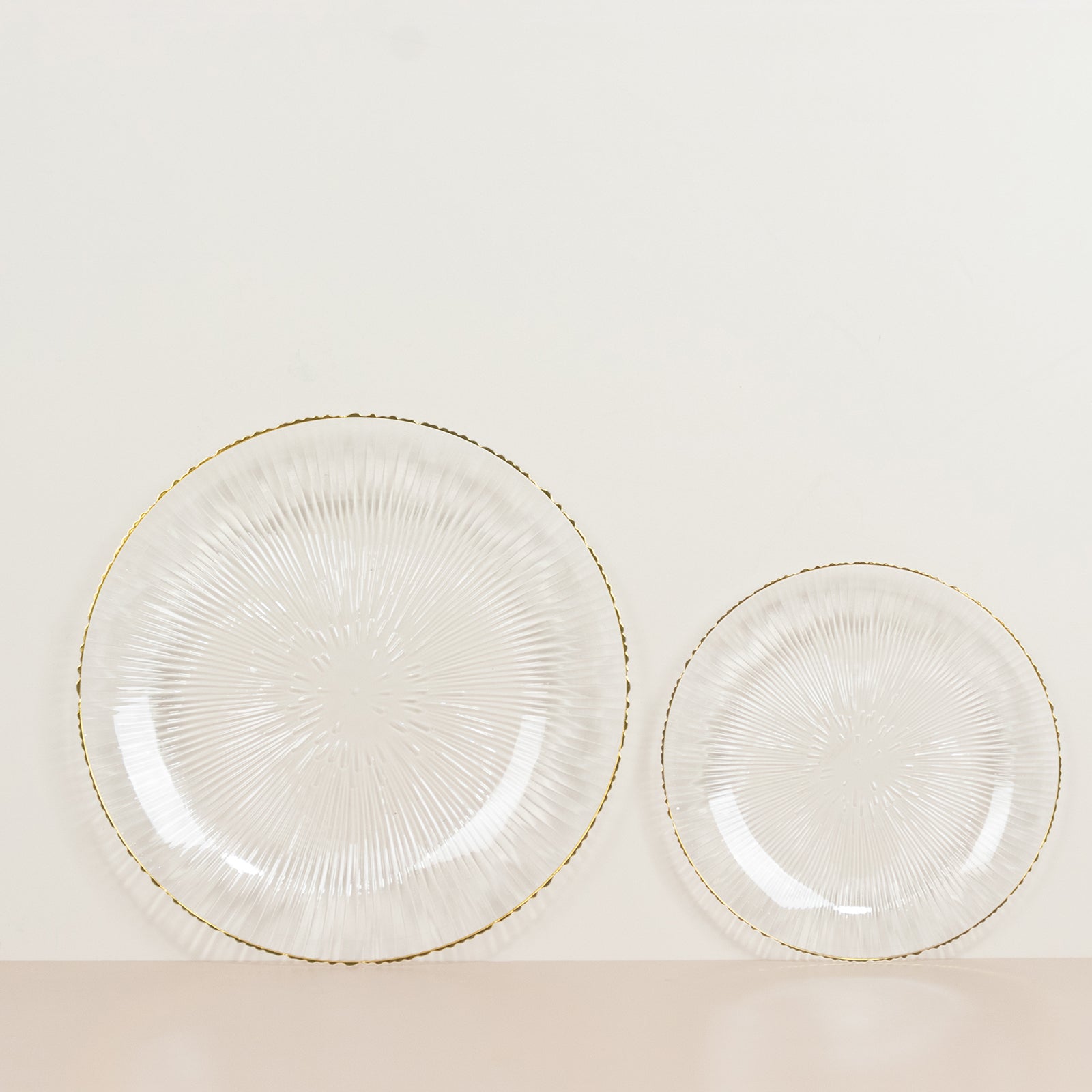 Clear plastic dessert plates with gold rim and ribbed sunburst pattern.