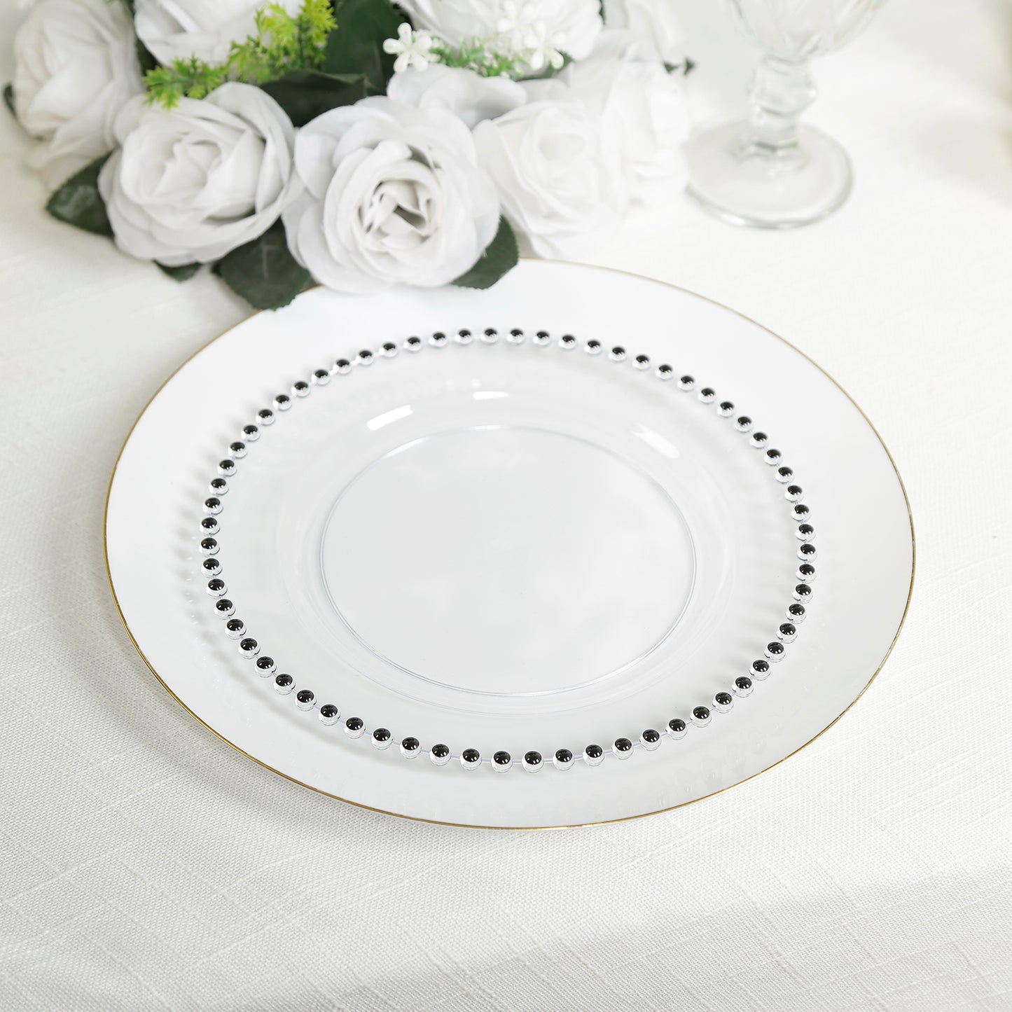 Clear plastic dessert plate with black beaded rim on a white table setting.