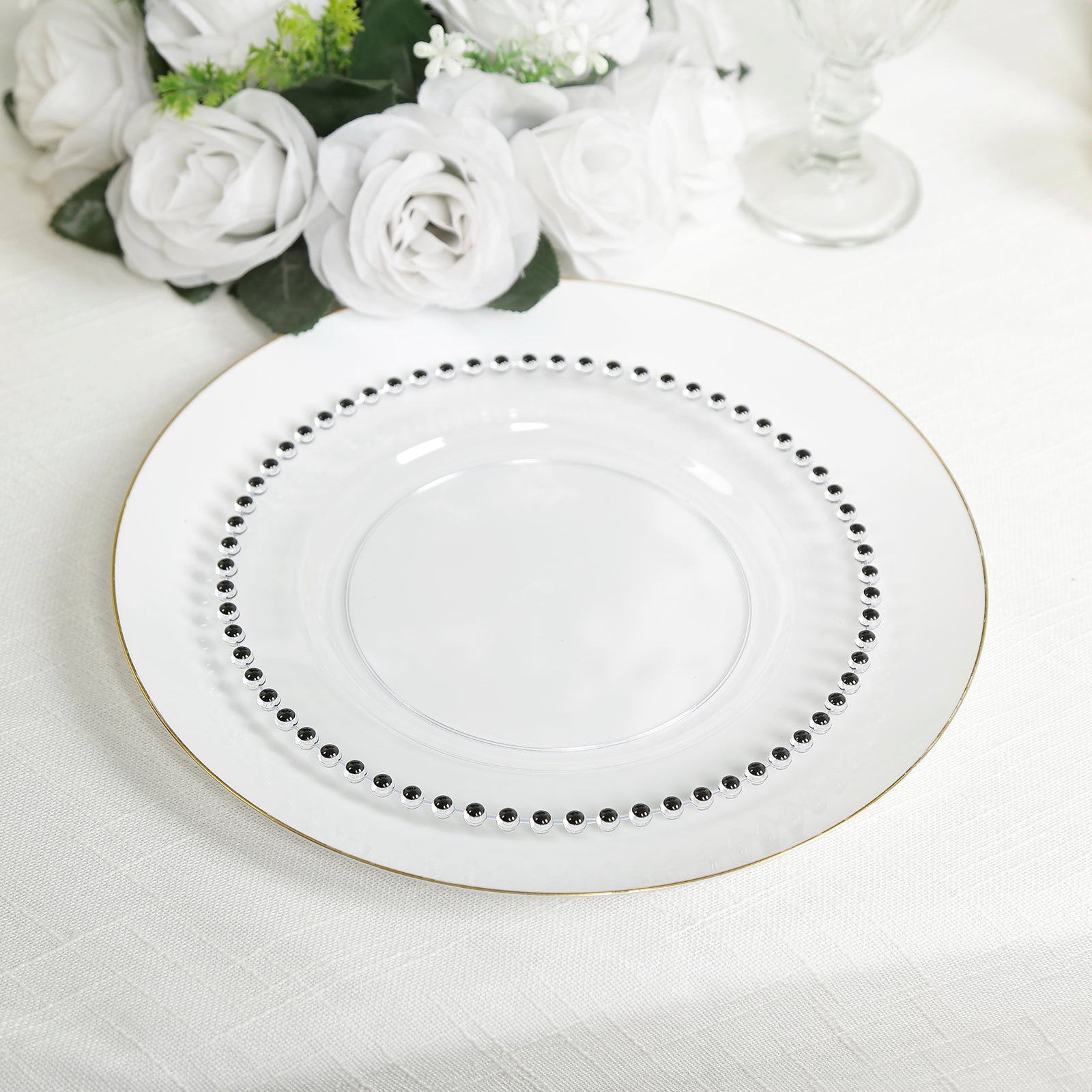 Clear plastic dessert plate with black beaded rim on a white table setting.