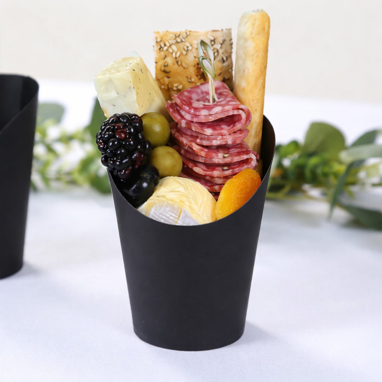 Black paper popcorn box filled with appetizers and snacks.