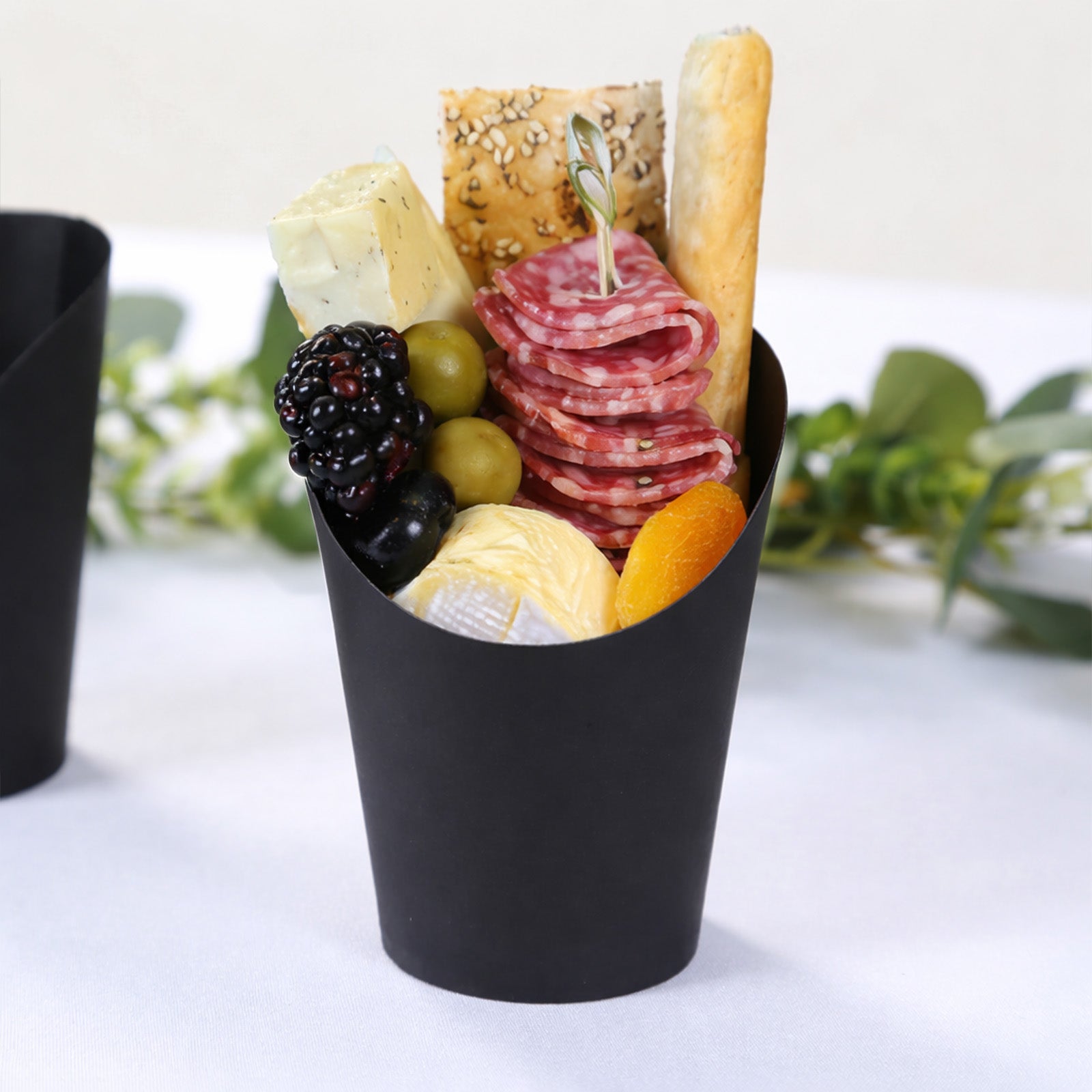 Black paper popcorn box filled with appetizers and snacks.