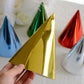Gold metallic foil cone party hat among other colorful hats.