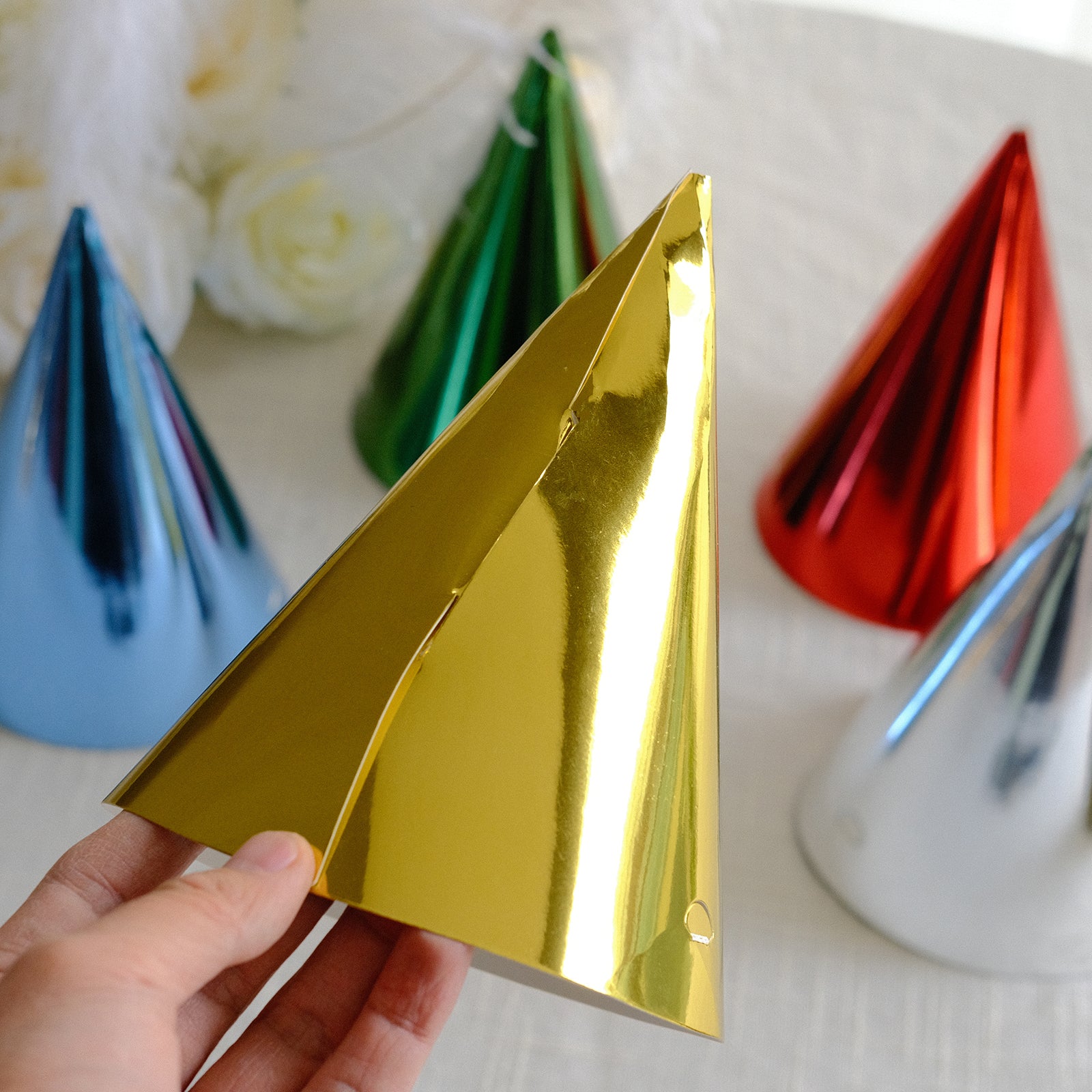 Gold metallic foil cone party hat among other colorful hats.