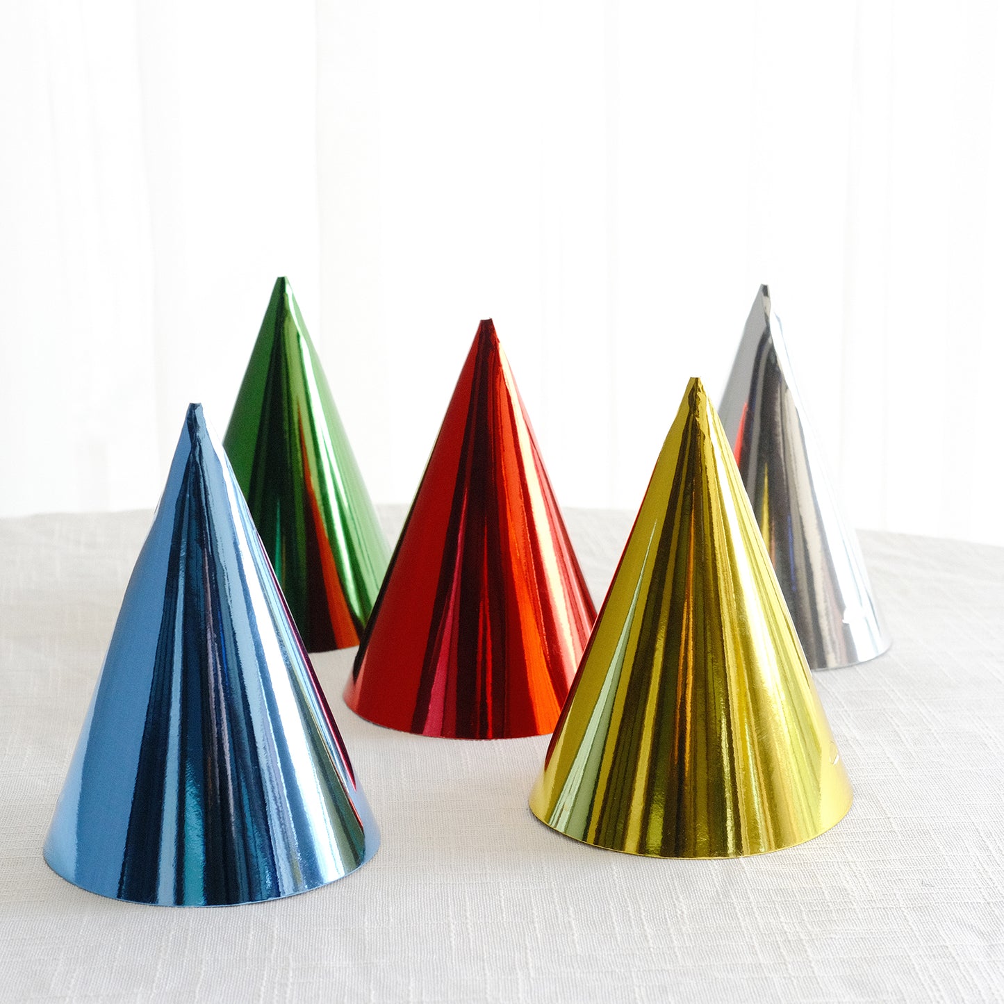 Mixed metallic foil party hats in blue, green, red, gold, and silver.