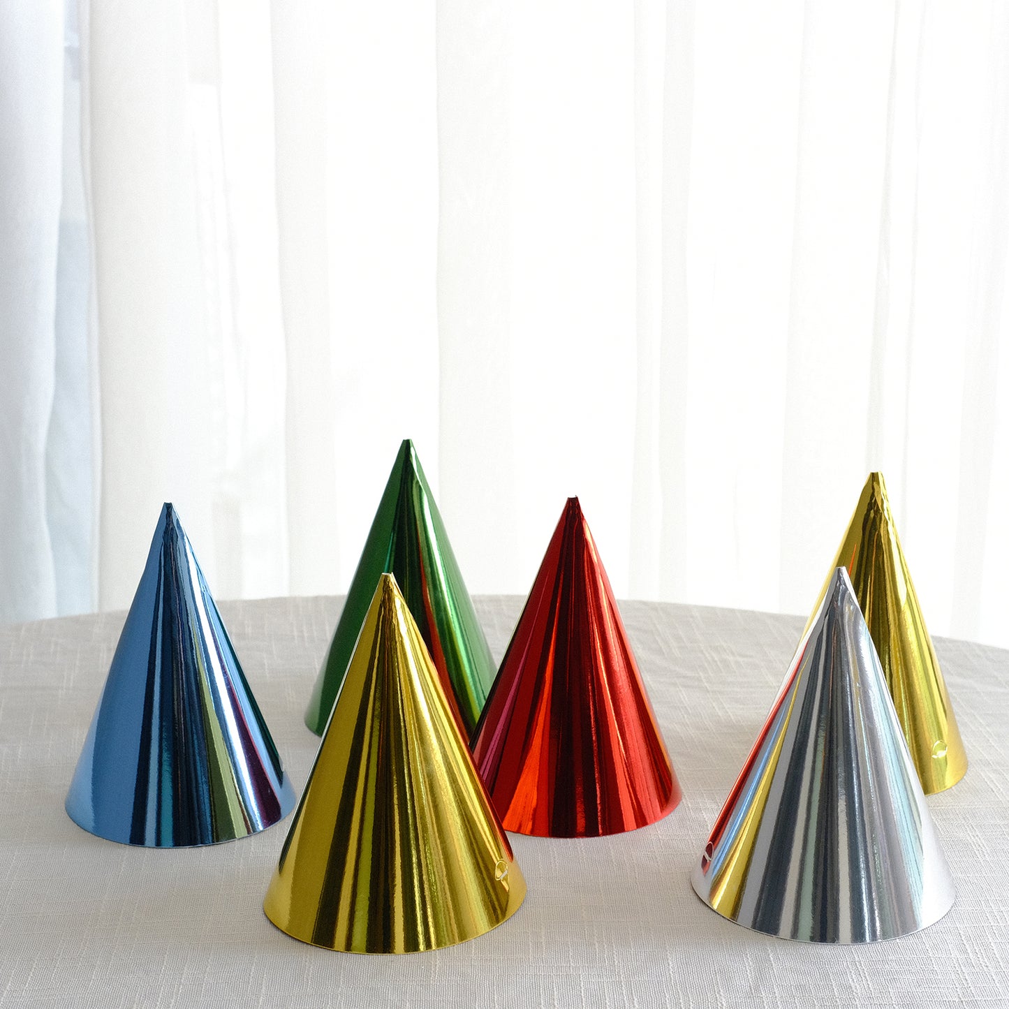 Mixed metallic foil party hats in various colors including red, green, and gold.