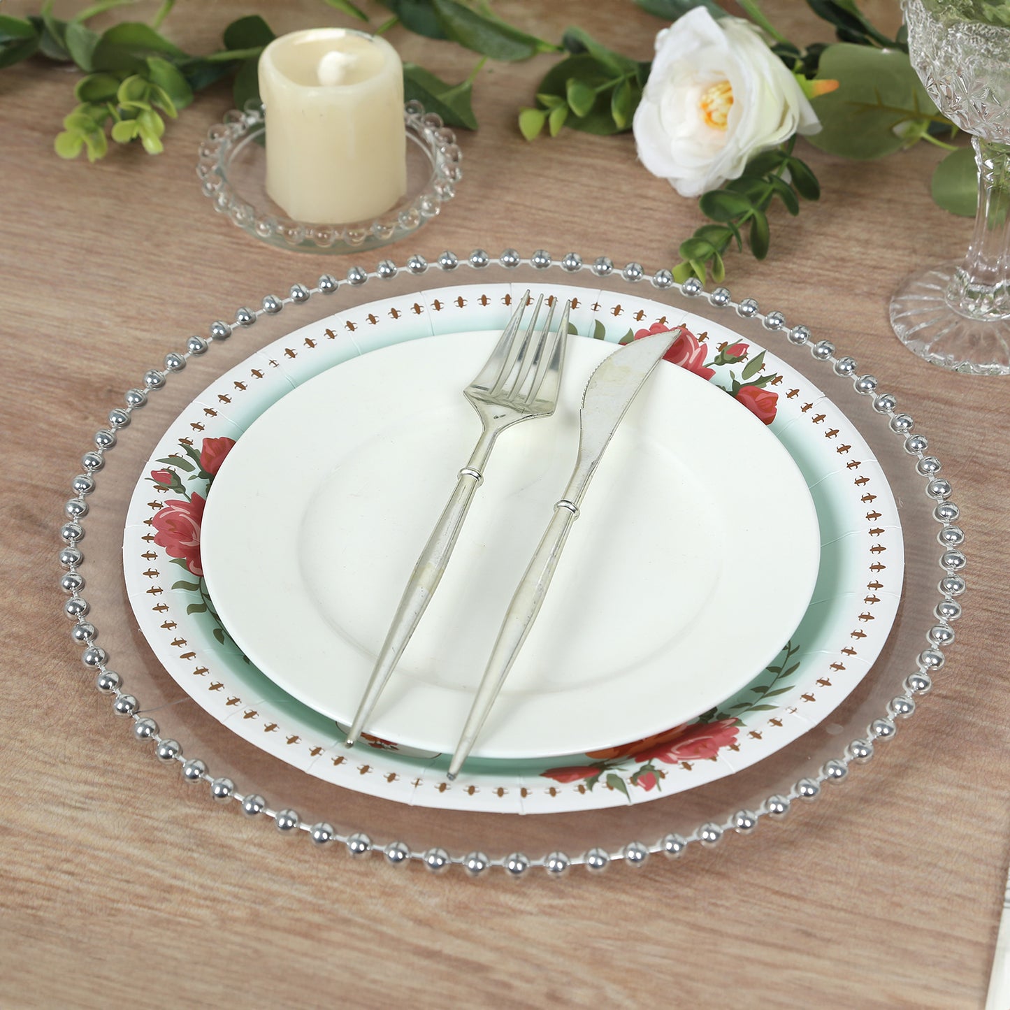 Light turquoise floral paper dinner plates with rose print on a wooden table setting.