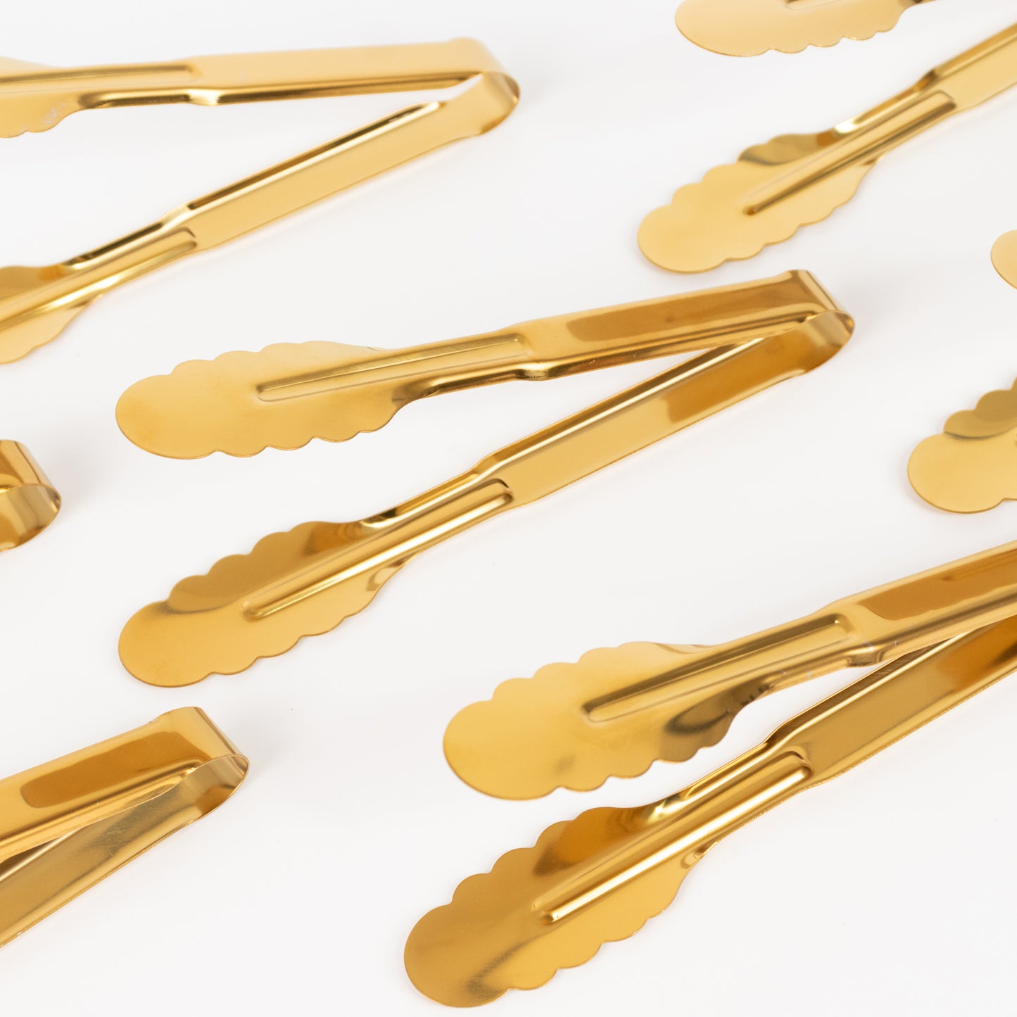 Gold metal kitchen tongs with scalloped edges, non-slip grip.