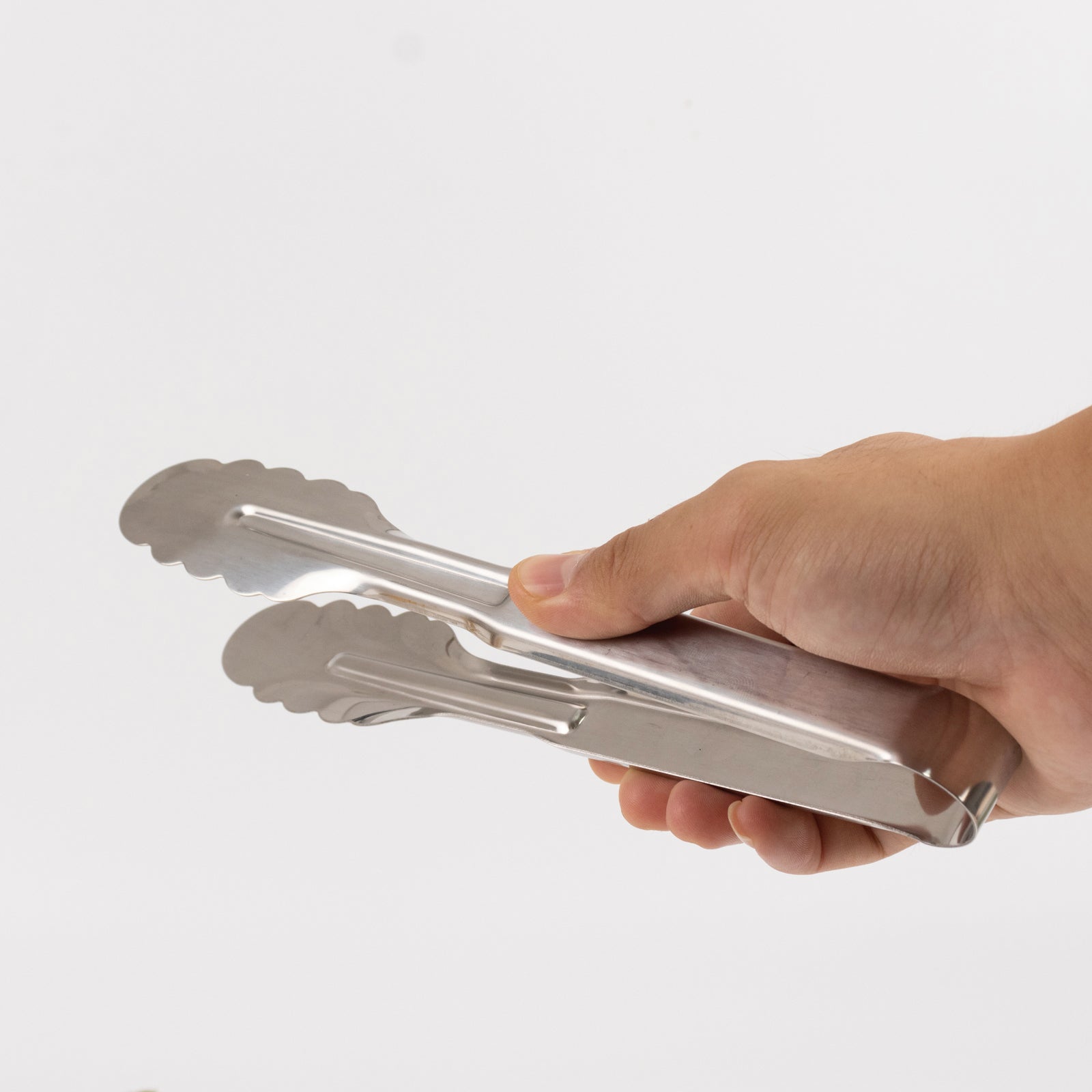 Silver metal kitchen tongs with scalloped edge, easy grip design.