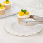 Silver metal kitchen tongs serving a dessert on a white plate.