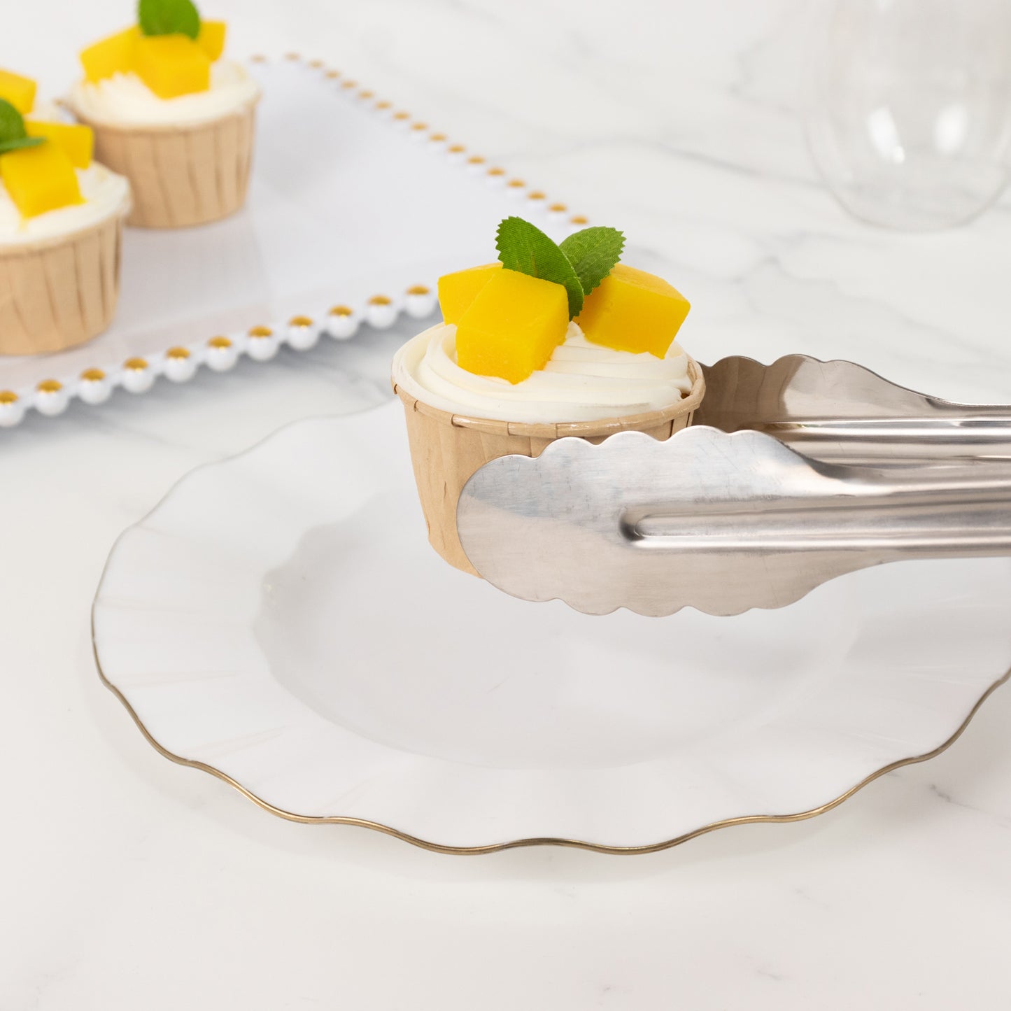 Silver metal kitchen tongs serving a dessert on a white plate.