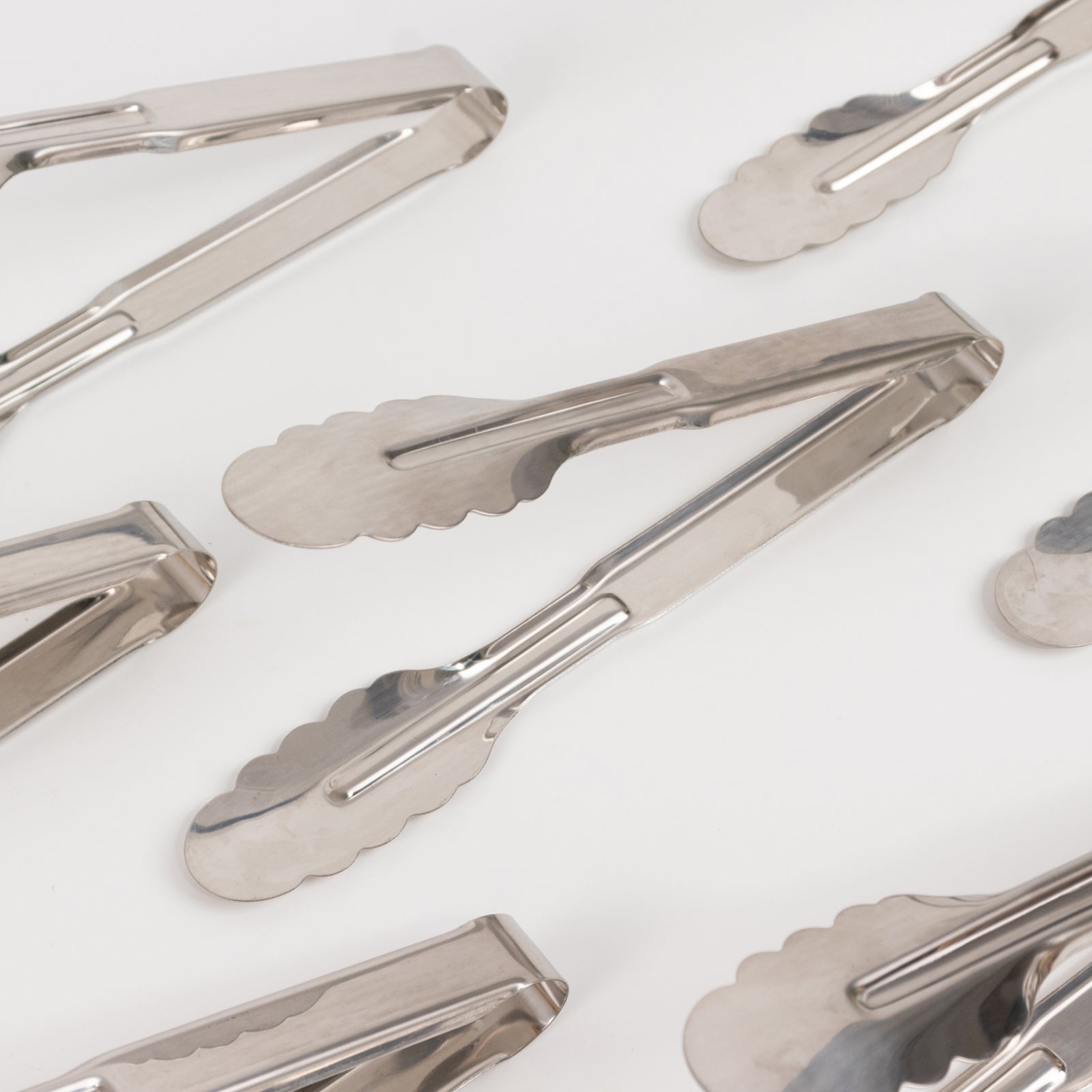 Silver metal kitchen tongs with scalloped edges, 9.5 inches long.