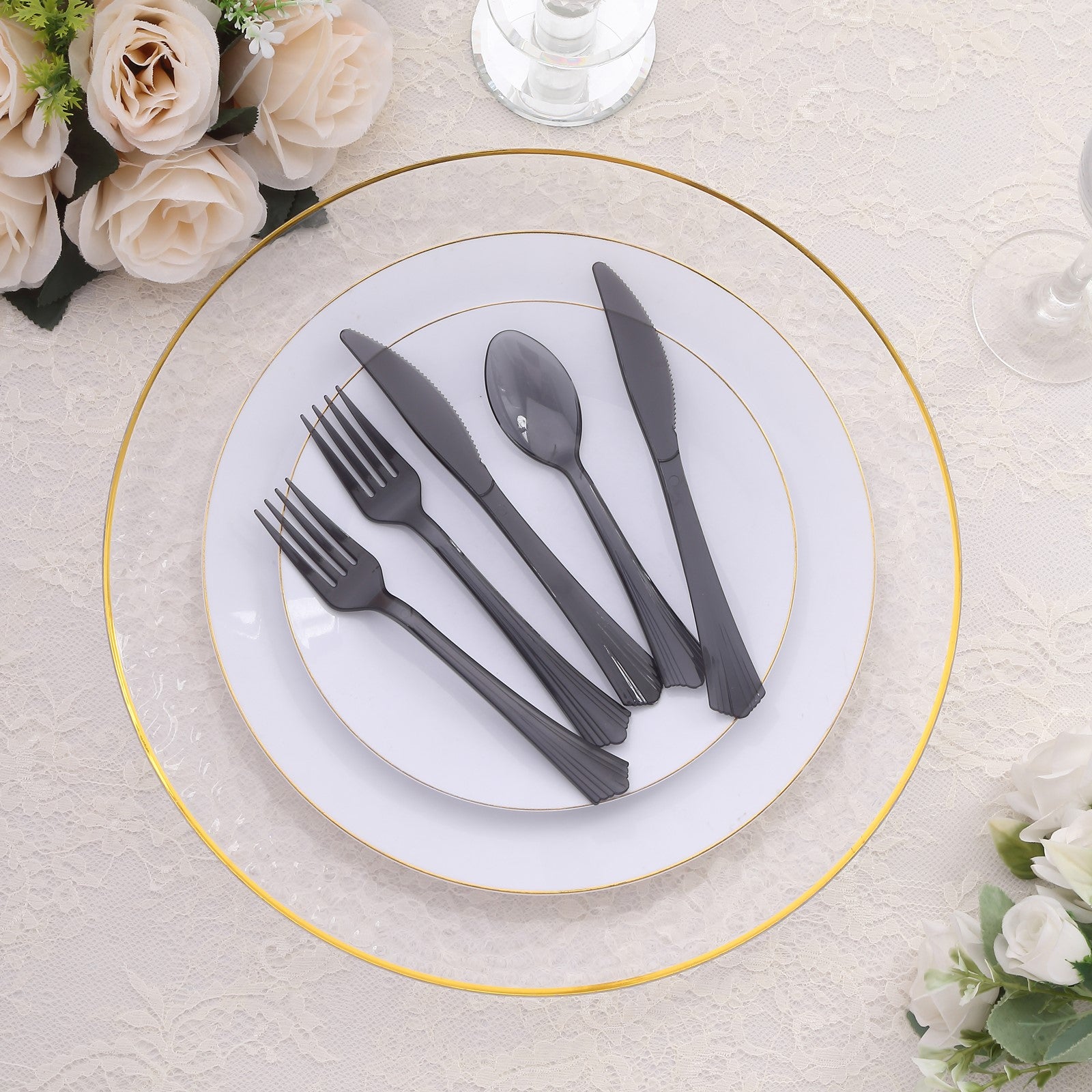 Transparent black disposable plastic cutlery set on a white plate.