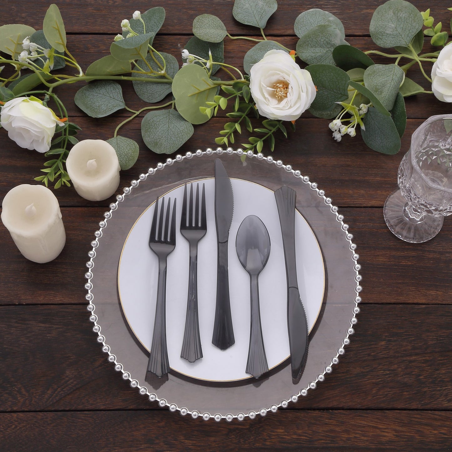 Transparent black disposable plastic cutlery set on a decorative plate.
